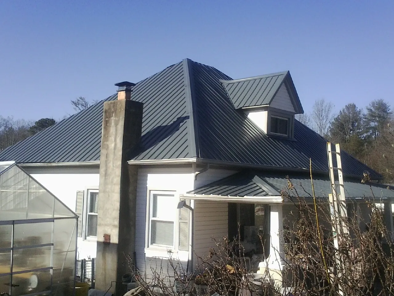 Dark blue standing seam metal roof on a white farmhouse with dormer — Slate & Tile Roof Repair by Roofing Brothers in Harrison City
