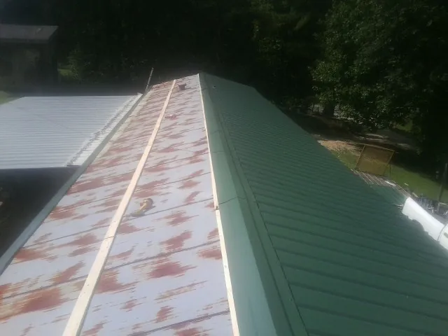 Old rusted panels beside newly installed green metal roofing — Wind Damage Roof Repair by Roofing Brothers in Harrison City