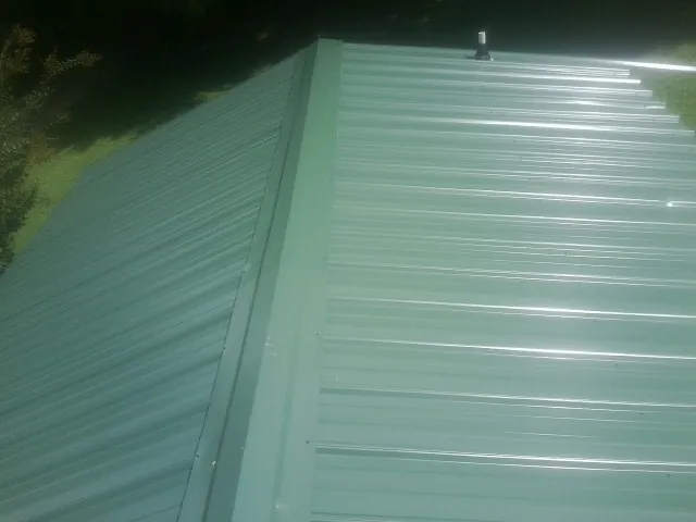 New green metal panels meeting at the ridge of a roof — Flat Roof Repair work by our crew in Harrison City