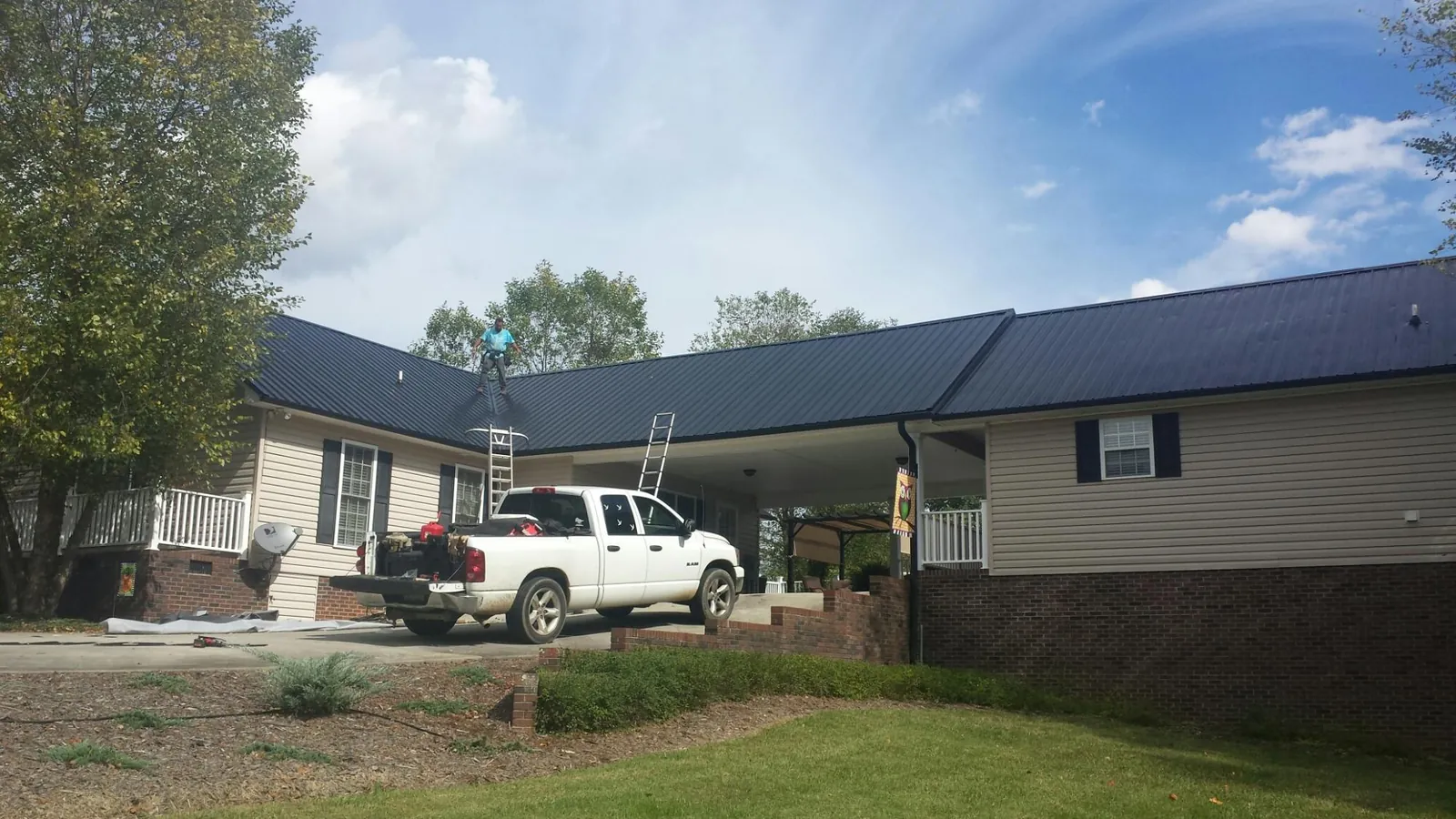 Black metal roof over a home and attached breezeway with ladders set in Harrison City