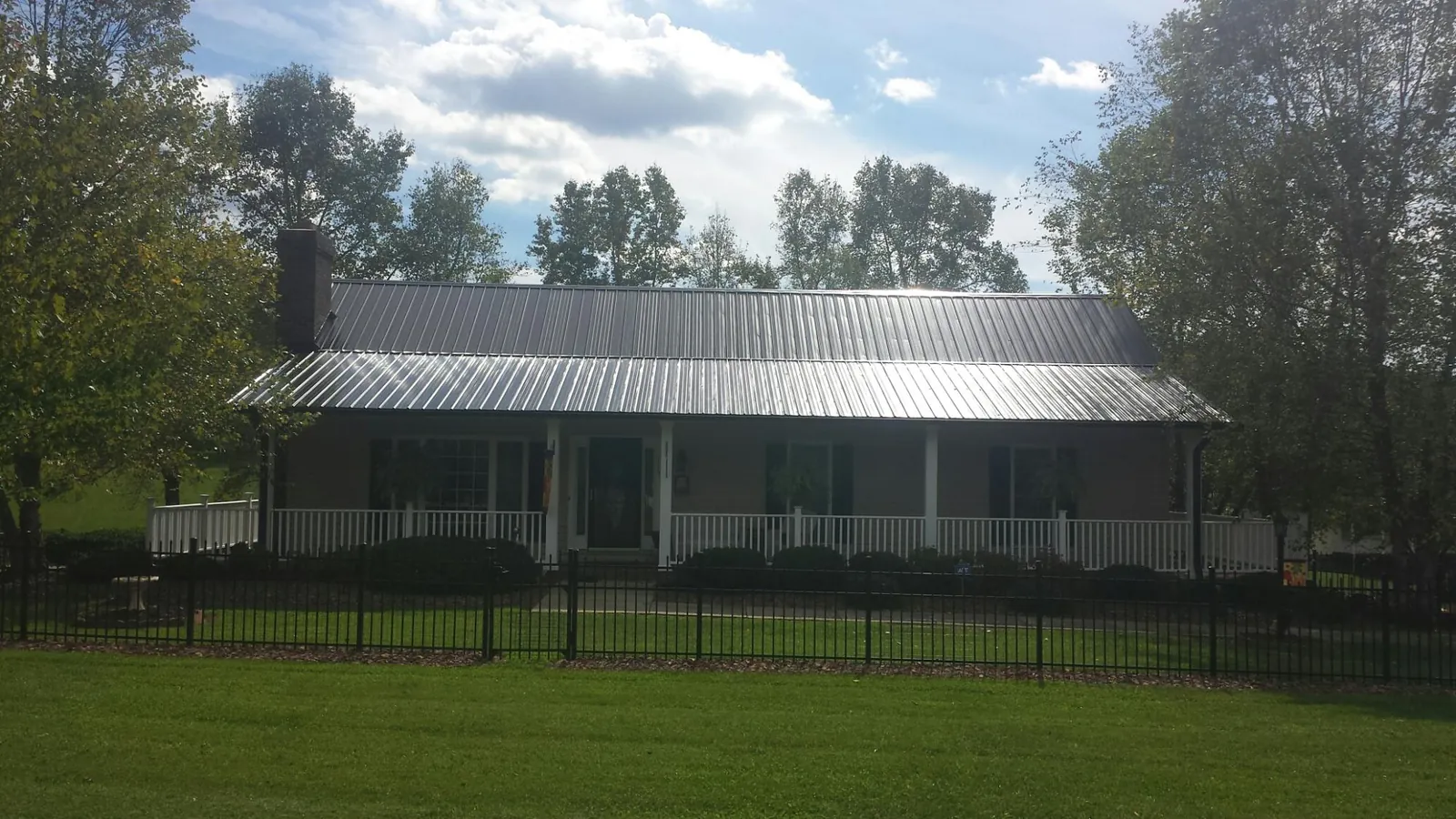Gray metal roof on a brick ranch with a full width front porch — Gutter Guard Installation work by our crew in Harrison City