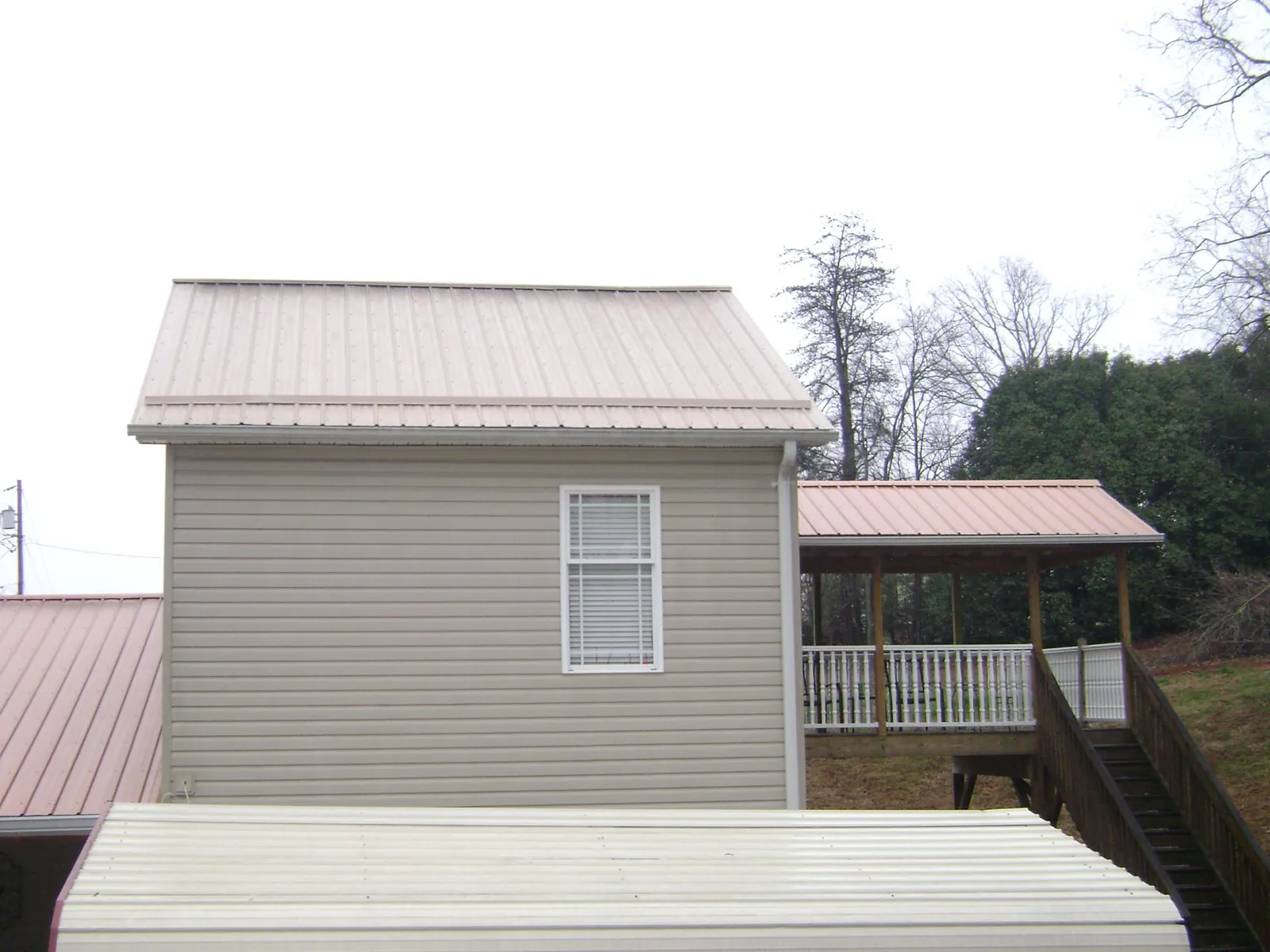 Tan metal roofs on a two story addition and attached porch, from a Roof Replacement job in Harrison City