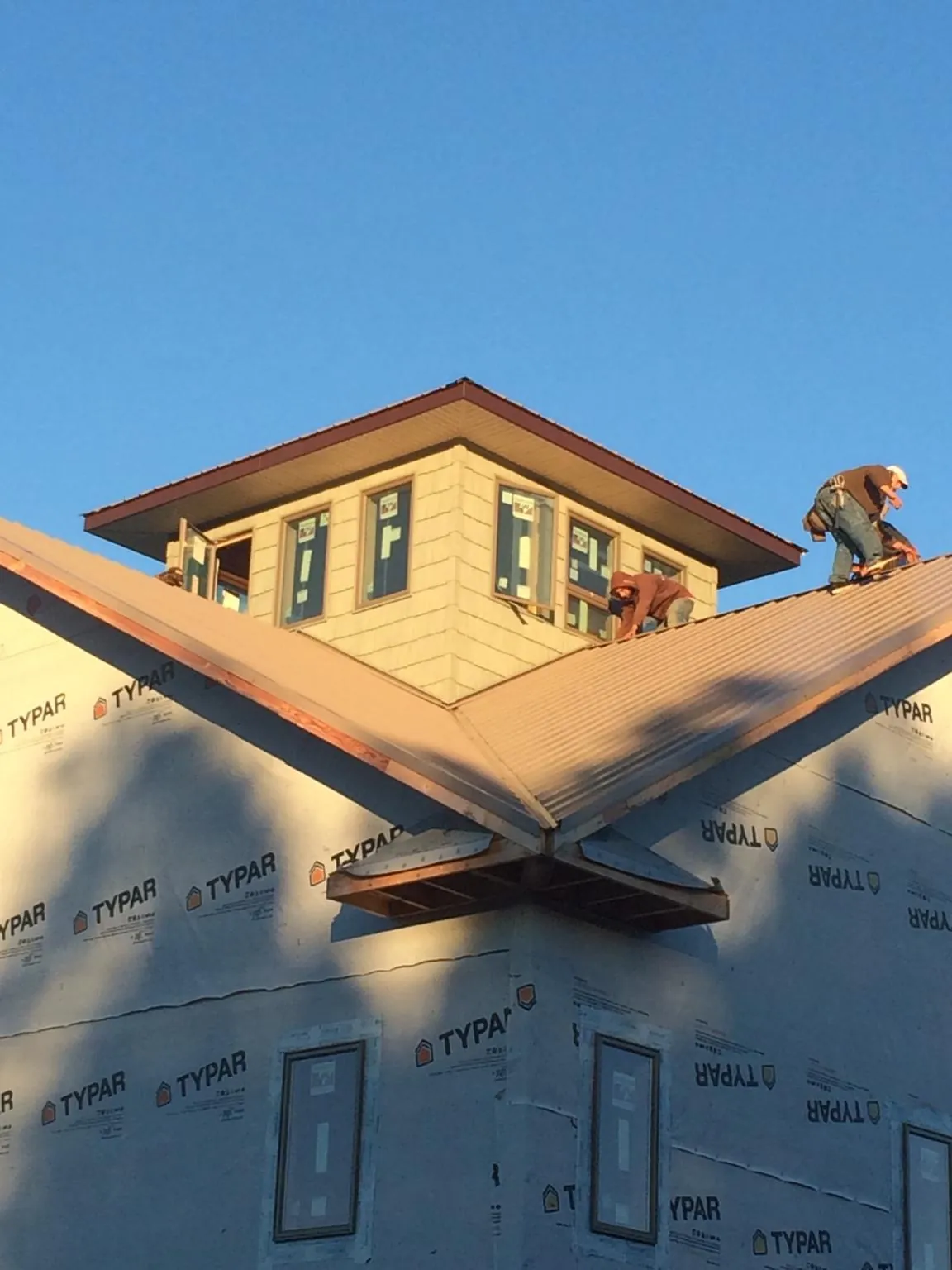 Roofers working around a rooftop cupola on a new metal roof at sunset — Roof Waterproofing in Harrison City by Roofing Brothers